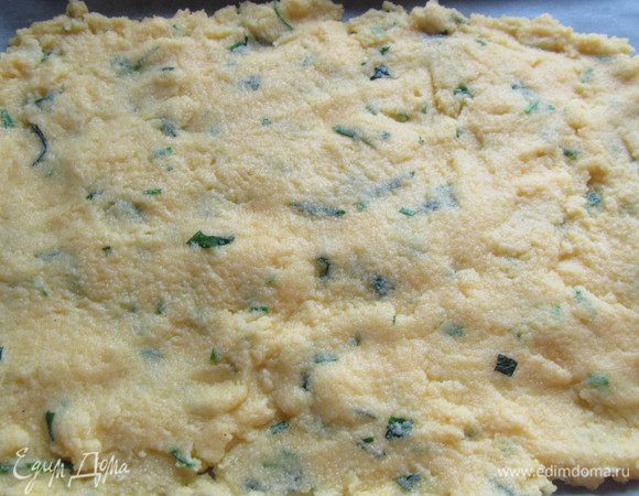 Берем противень или большую доску. Выстилаем ее бумагой для выпечки. Выкладываем нашу поленту и распределяем ее тонким слоем примерно 1 см. Оставляем минимум на 5 минут остывать. А вообще, чем дольше, тем лучше. 
