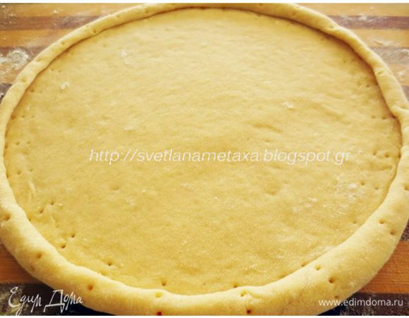 Готовое тесто делим на 2 части. Из одной части раскатываем круглую лепешку, диаметром чуть больше диаметра формы (26 см). Форму застелить  пергаментной бумагой и положить на нее нижнюю лепешку. Края лепешки завернуть во внутрь. 