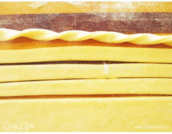 Из второй части теста раскатываем овальную или прямоугольную лепешку и ножом для пиццы разрезаем на длинные полоски, примерно 1 см шириной. Каждую полоску скручиваем в спиральку.