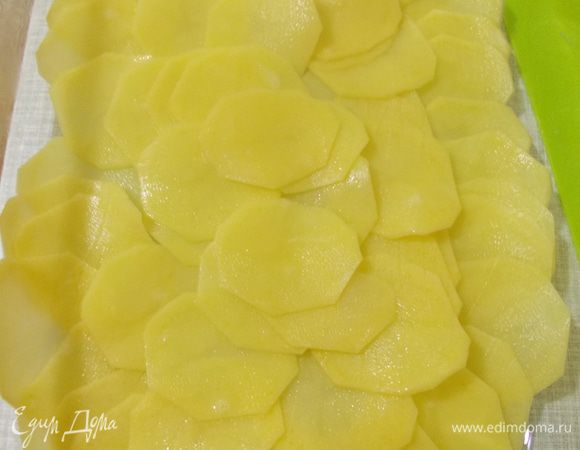 Разогреваем духовку до 200 градусов. В форму выкладываем тонким слоем пласты картошки.