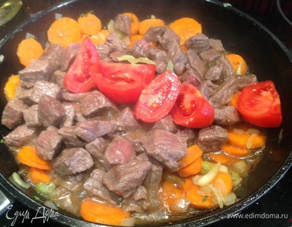 Верните в кастрюлю мясо, добавьте томаты (предварительно надрежьте, залейте кипятком на 2 мин, после чего  опустите в холодную воду и очистите, нарежьте на четвертинки) и вино. Дайте жидкости немного впитаться в мясо и овощи, затем добавьте бульон (или воды), лавровые листья и  немного ворчестерского соуса.