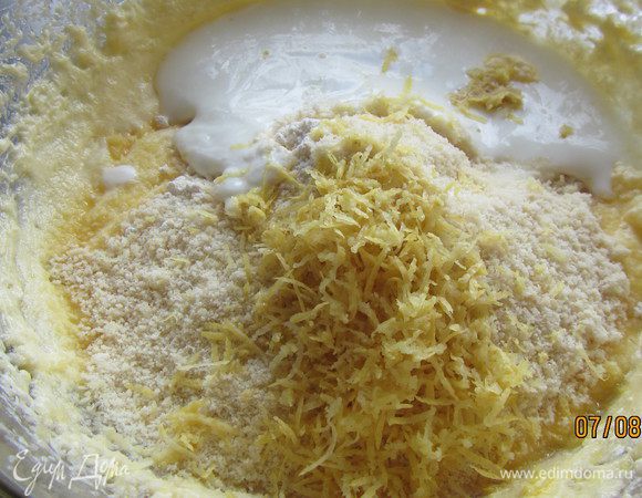 Добавляем муку, смешанную с разрыхлителем, йогурт, миндаль и цедру 2 лимонов. Все перемешиваем лопаткой. 
