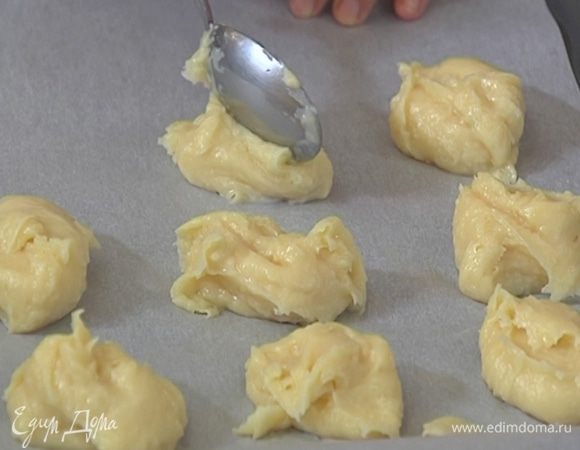 Противень выстелить бумагой для выпечки и смоченной в холодной воде ложкой выложить небольшие круглые эклеры.