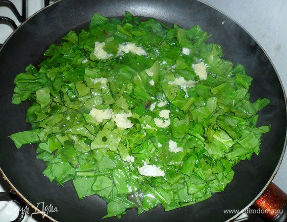 Ставим воду на пасту, пусть закипает. А мы тем временем на разогретую сковороду выкладываем шпинат, добавляем немного воды, оливковое масло и выдавливаем чеснок. Накрываем крышкой и тушим 7-9 минут  пока не выпарится вода.