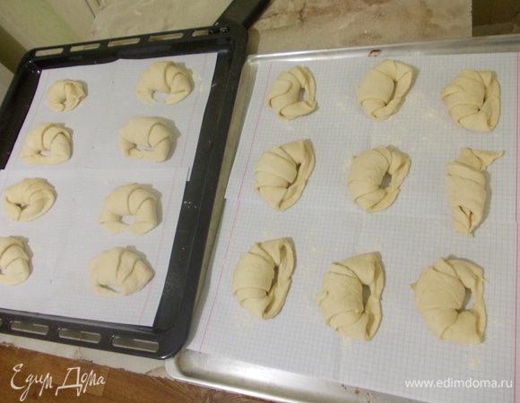 Выстелить бумагу на противень, посыпать мукой. Выложить круассаны. Накрыть полотенцем и оставить их на 1 час. 