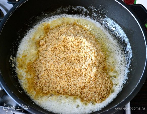 В сковороде с тяжелым дном растопить сливочное масло и добавить к нему ореховую крошку.