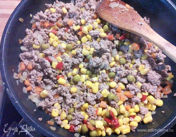 Вмешиваем горошек, кукурузу и мелким кубиком порезанный красный перец, тушим несколько минут на среднем огне. 