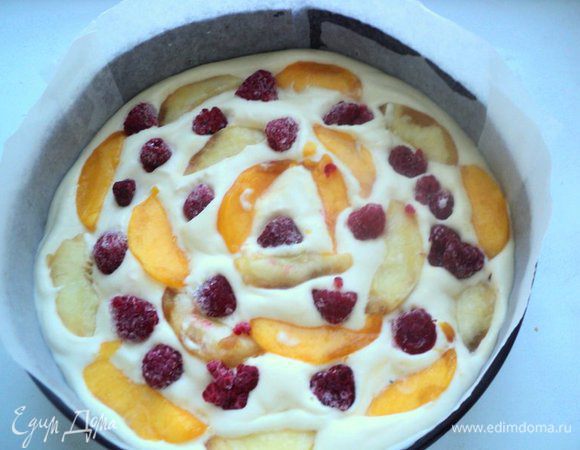 Вылить 2/3 суфле в форму, хорошо заполнив промежутки между бисквитом и формой. На суфле выложить порезанный на пластинки персик и малину. 