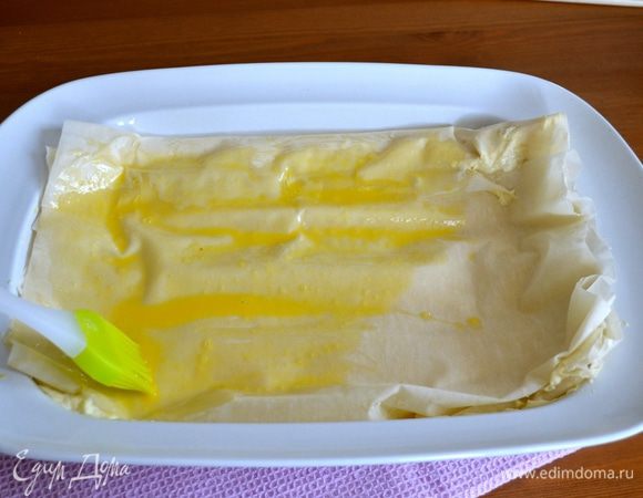 Когда вся начинка закончится, накрыть пирог сверху сухим листом (или двумя!) теста фило и завернуть свисающие края к центру, чтобы начинка не вытекала в процессе выпечки. Смазать верх пирога яйцом и поставить выпекаться в разогретую духовку на 50 минут, до приобретения пирогом золотистого цвета. 