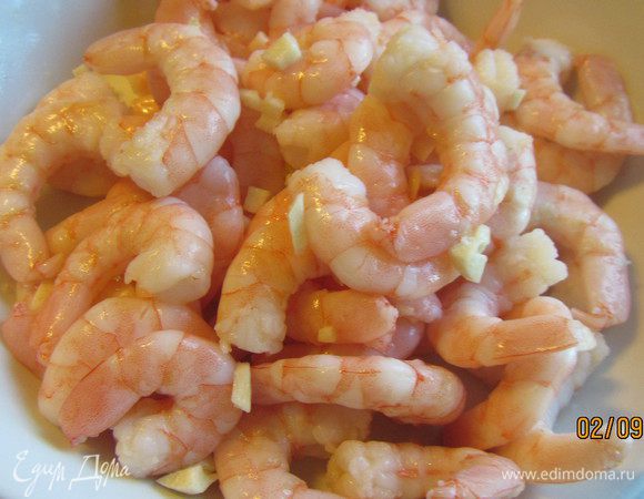 Чеснок мелко рубим, добавляем его и пару столовых ложек оливкового масла к креветкам и оставляем мариноваться (минут на 20).
