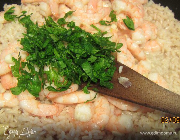 Зелень мелко рубим и добавляем ее и креветки в ризотто. Солим, перчим и готовим еще минут 5.
