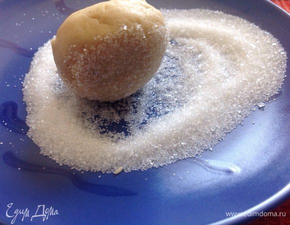 Из теста сформировать шарики размером с грецкий орех, обвалять хорошо в сахаре и выложить на противень, застеленный бумагой для выпечки, на расстоянии 5 см. друг от друга (это важно!). Каждый шарик чуть придавить!
