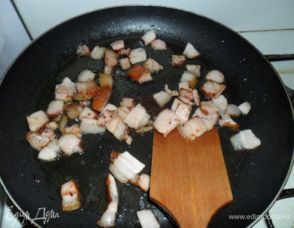 Пока паста варится, мы на разогретую сковороду вливаем оливковое масло и высыпаем нарезанный кубиками бекон. Помешивая обжариваем его до золотистого цвета.