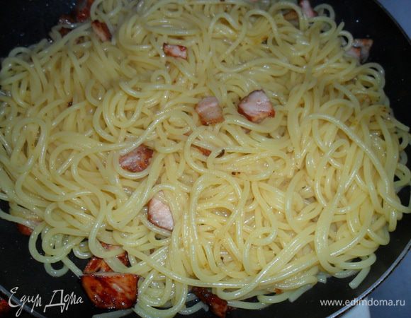 С готовой пасты слить воду (не забыв оставить чашку) и добавить к бекону на сковороду. Подержать на небольшом огне 2-3 минуты постоянно помешивая.