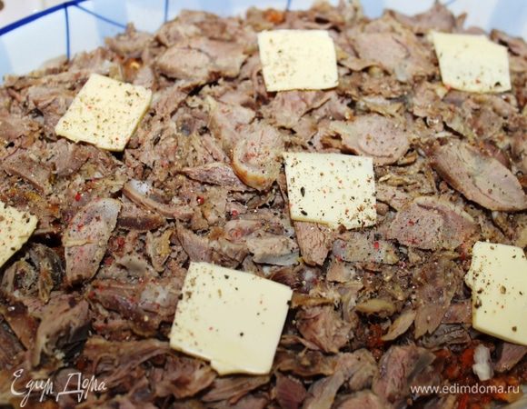 Присыпать еще одной часть сыра (1/4) и выложить нарезанное тонкими пластинками отварное мясо. Сверху разложить остатки сливочного масла (25 грамм), посолить и поперчить.