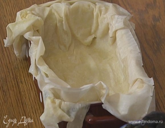 Второй пласт теста смазать маслом, свернуть пополам, смазать маслом верхний слой и выложить его на первый пласт смазанной стороной вниз.