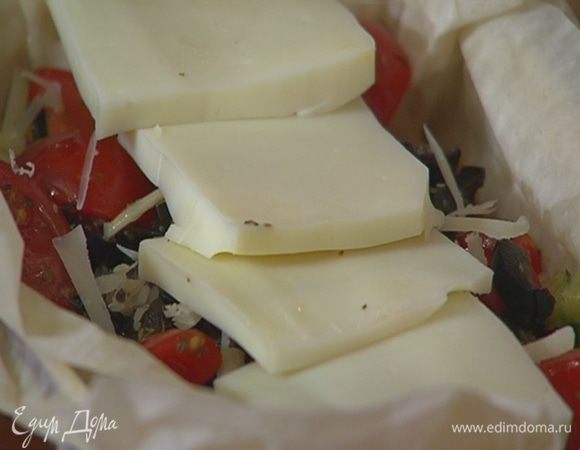 В форму с тестом выложить баклажаны, цукини, посыпать натертым твердым сыром, затем выложить помидоры с маслинами, сбрызнуть оливковым маслом Extra Virgin, сверху разложить ломтики адыгейского сыра.