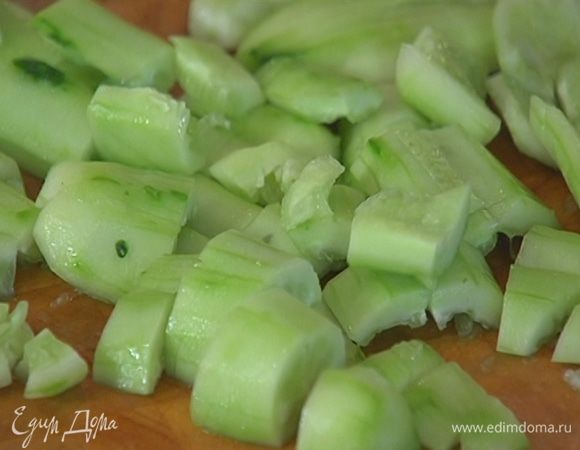 Плоской стороной ножа слегка раздавить половинки огурцов, затем нарезать их крупными кусками.