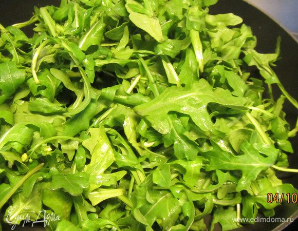 Займемся начинкой для нашей пиццы. Руколу моем, сушим и тушим несколько минут на оливковом масле. Она значительно уменьшится в объеме.


