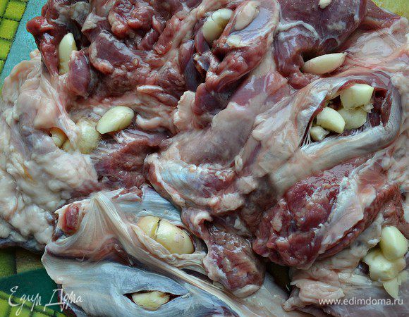 Сделайте в ноге несколько неглубоких надрезов и вставьте в них чеснок (2 зубчика оставить для топинадо). Немного сверху подсолить.