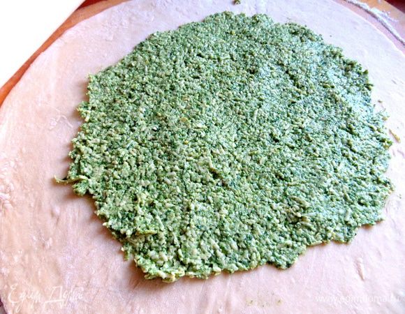 Делим тесто пополам (или больше), каждую часть тонко раскатываем, кладём половину всей начинки, размазываем по центру. На доску понадобится ещё около полстакана муки.