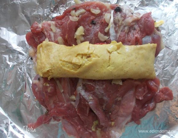 Затем сворачиваем омлет,а затем уже два пласта мяса. Их нужно положить так,чтобы удалось их скрутить вместе,чтобы один кончик мяса,лежал на другом внахлест.