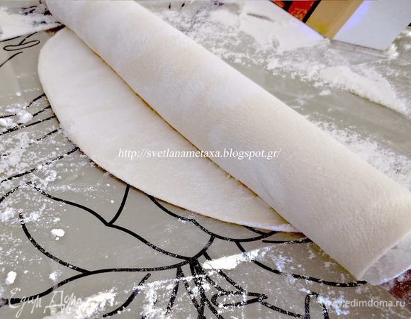 Раскатав тонкий пласт, накручиваем его на скалку и продолжаем раскатывать, руками вытягивая тесто в стороны.