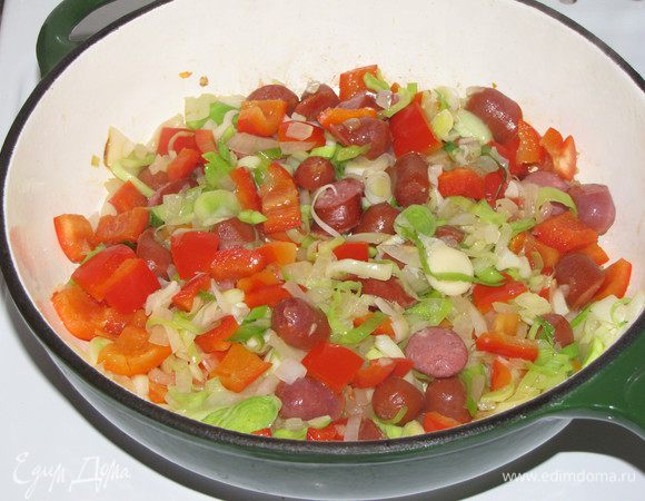 Добавить измельченный чеснок, лук порей, болгарский перец и колбаски. Перемешать и жарить 5 минут на небольшом огне.