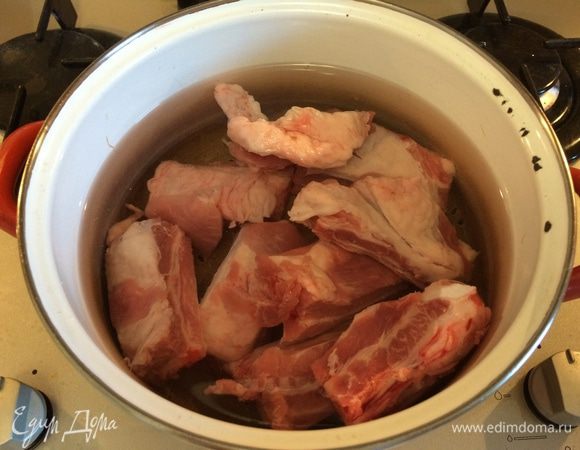 Свиные ребрышки промыть в холодной воде, сложить в кастрюлю, залить 2,5 литрами воды и поставить на средний огонь. Когда первый бульон закипит, слить его, переложить мясо в чистую воду и снова довести до кипения. Затем убавить пламя до самого слабого и варить мясо около 40 мин.