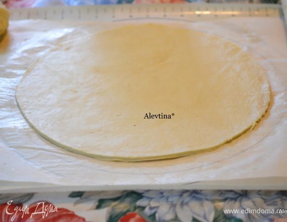 Поделить тесто на 2 части. Раскатать один кусок теста в круг. Я раскатываю через бумагу для выпечки, припылив рабочий стол мукой.
