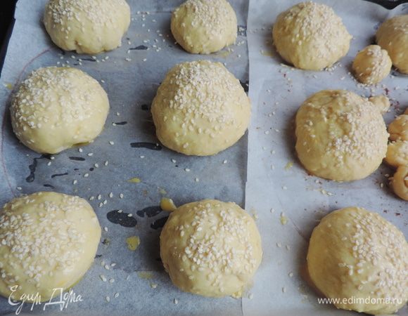 Подошедшее тесто необходимо слегка обмять и разделить на 12 равных частей. 
Каждый кусочек теста расплющиваем в лепешку, по желанию кладем начинку, защипываем края и формируем круглую булочку. Выкладываем булочки на противень с бумагой, смазываем слегка взбитым яйцом, посыпаем кунжутом. Оставляем минут на 15.