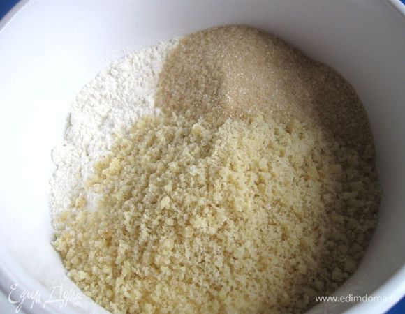 Просеять пшеничную муку, добавить сахарный песок, ванильный сахар и  измельченный миндаль.