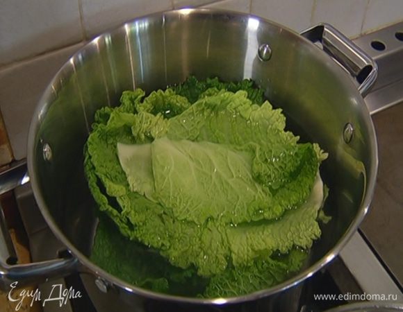 Капустные листья, срезав грубые черенки, опустить на 5–7 минут в кипящую воду, затем откинуть на дуршлаг.