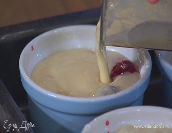 На дно разогретых формочек выложить примерно по 10 ягод вишни, посыпать их оставшейся сахарной пудрой, затем влить тесто.