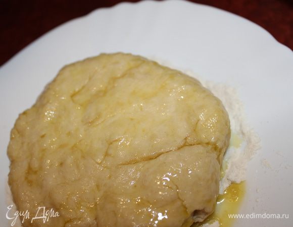 В чашу с мукой и солью налить масло и воду, замесить тесто. Oно может показаться туговатым, но после того как постоит под крышкой или плёнкой 30 минут, но сначала его необходимо расплюснуть и смазать оливковым маслом по поверхности. По истечению времени оно приобретёт гладкую приятную структуру и будет очень податливым.