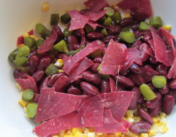 Корнишоны режем кубиками, и колбасные изделия также. Добавляем их в салатницу.
