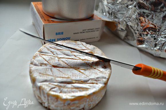 Достаньте сыр из коробки, разверните бумагу. Сделайте на поверхности сыра несколько надрезов.