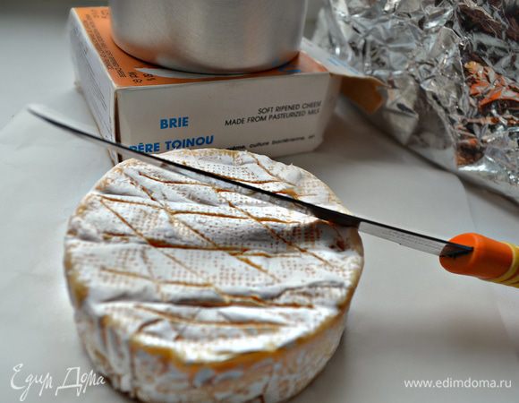 Достаньте сыр из коробки, разверните бумагу. Сделайте на поверхности сыра несколько надрезов.