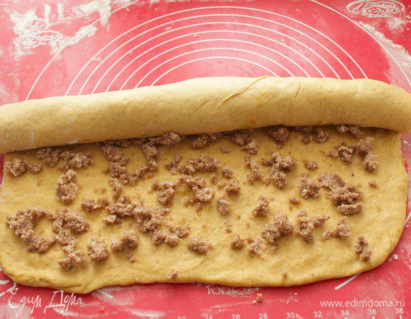 Когда тесто подошло, раскатать его в прямоугольник толщиной около 1 см.
Аккуратно смазать тесто сливочным маслом и равномерно посыпать ароматным сахаром.