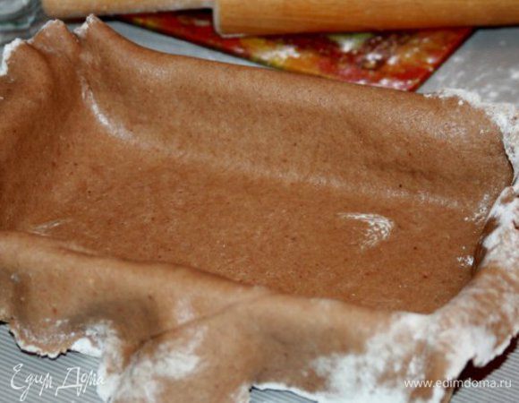 Форму смазать маслом. Постелить на стол пергамент (или пищевую пленку) и раскатать на нем тесто очень тонко! Толщиной 2 мм. После этого одним резким движением перевернуть тесто на форму и аккуратно его в ней уложить. Края обрезать.