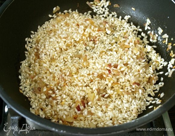 Через 5-6 минут добавить к луку сразу весь рис. Предварительно не промывать! Дать подержать вместе пару минут. Через минуту увеличить огонь и влить белое сухое вино. Дать ему выпариться.