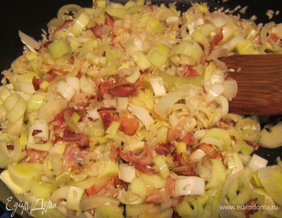 Форму, в которой будем запекать ризотто, ненадолго поставим в духовку, чтобы прогрелась. Тем временем добавляем в сковороду рис и лук-порей. Готовим несколько минут, чтобы все хорошо пропиталось.
