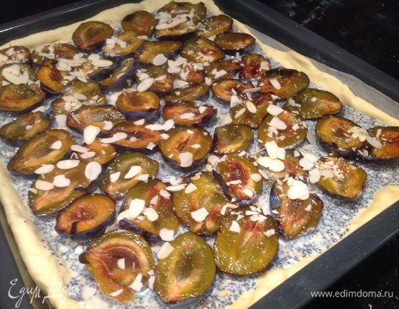 Сверху выложите сливы, кожицей вниз, и присыпьте миндальными лепестками.