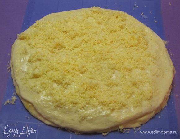 Раскатать третий кусок теста в круг, выложить на второй круг теста с сыром. Смазать растопленным сливочным маслом, посыпать тертым сыром.