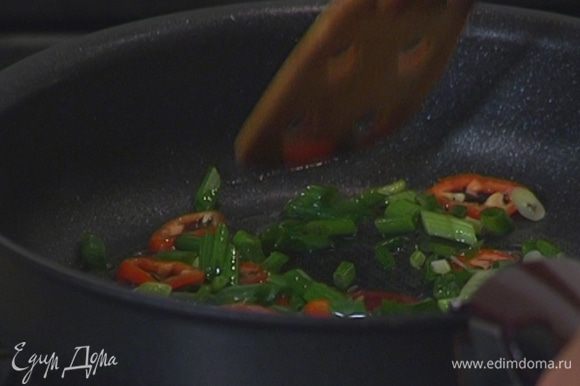 Разогреть в сковороде со съемной ручкой оливковое масло и прогреть лук и перец чили.