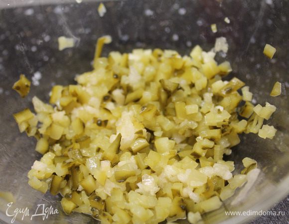 Теперь готовим соус.
Очень мелко нарезаем маринованный огурец и смешиваем с измельченным чесноком.