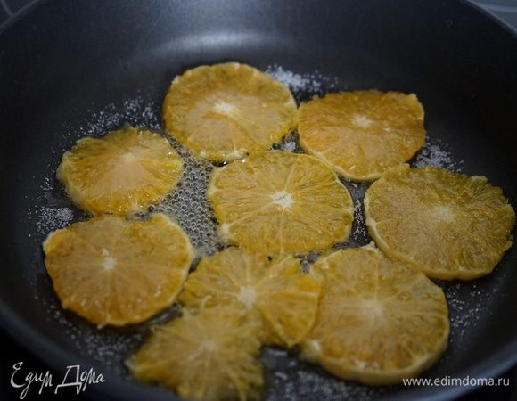 Для слоя из карамелизированных апельсинов: очистить  апельсин от кожуры, лучше это сделать ножом, а не руками, срезая весь белый слой до оранжевой мякоти. Нарезать апельсин довольно тонкими кружочками, выложить их на сковороду и присыпать сахаром. Тушить в сиропе по 2-3 минуты с каждой стороны. Выложить на кекс. 