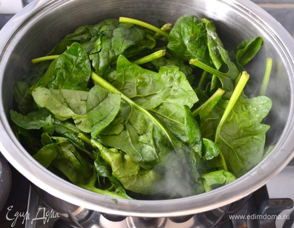 Шпинат вымыть. Не стряхивая сильно воду с вымытых листьев, положить шпинат в большую кастрюлю и поставить на огонь. Накрыть крышкой (можно влить полстакана воды).