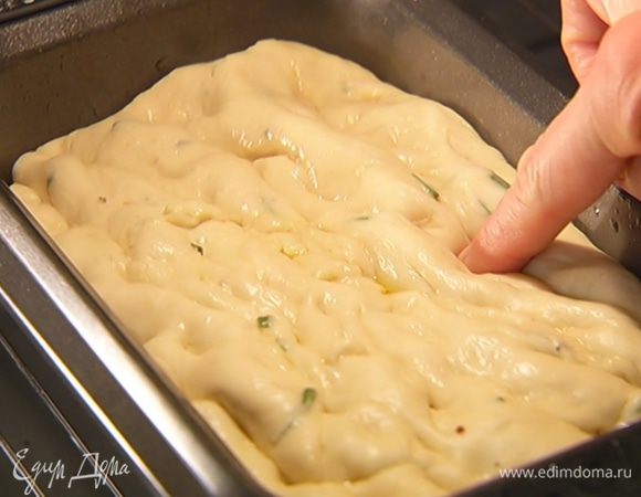 Прямоугольную форму для выпечки смазать оставшимся оливковым маслом, выложить тесто, обмять пальцами и вернуть в духовку на 15 минут для расстойки.