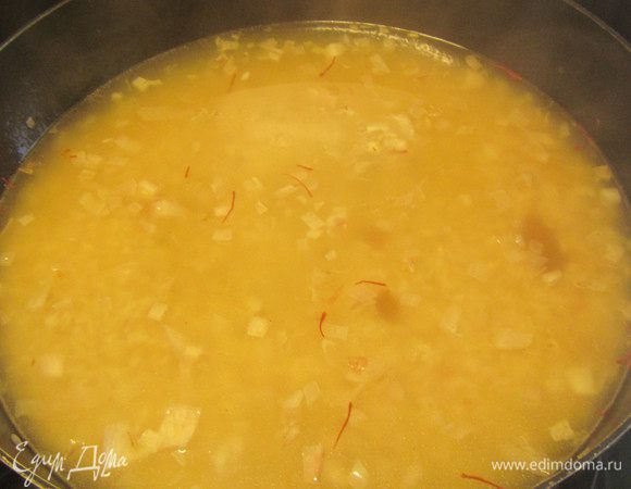 Добавляем вино, шафран и бульон. Доводим до кипения, затем уменьшаем огонь, накрываем крышкой и готовим минут 15-20 до мягкости риса. Снимаем с огня.
